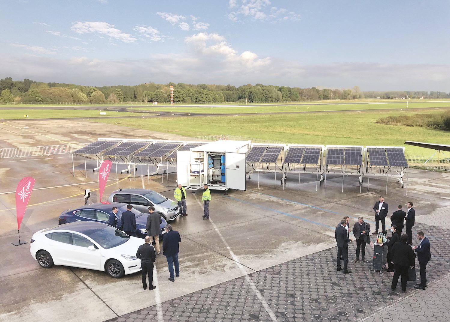 Opslagcontainer met zonnepanelenveld en laadpunten voor elektrische auto's op een bedrijfsterrein