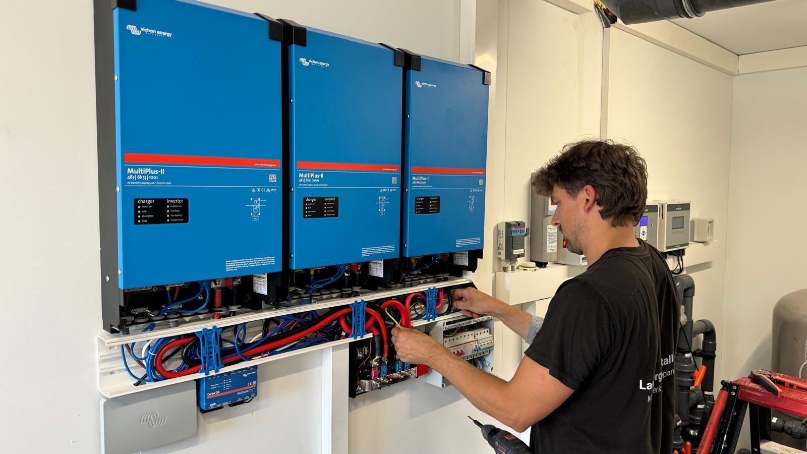 Monteur Daniël sluit drie Victron MultiPlus-II omvormers aan in een technische ruimte