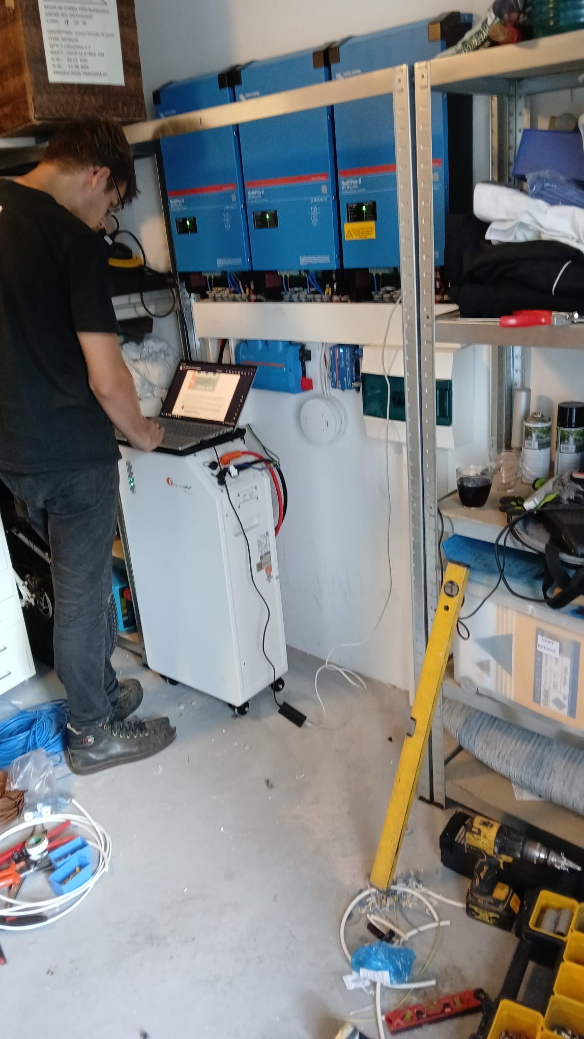 Monteur stelt het Victron-systeem in met de laptop bij een batterij in een garage in Assen